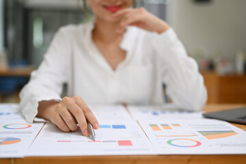 Professional businesswoman doing some paperwork, analyzing financial graph chart data on wooden office desk