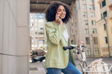 Curly-haired pretty woman with a bike in the street