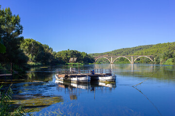 Obraz premium A boat with which people used to cross the river before the construction of bridges, with the railroad bridge.