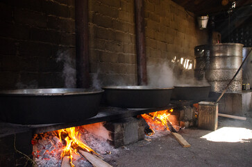 big cauldrons over fire, cooking. Wood fire.
