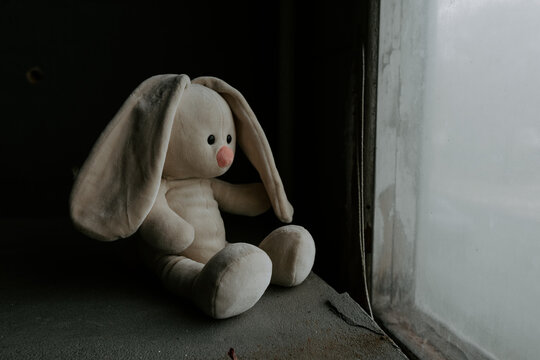 Toy bunny sitting next to window. Loneliness concept. International missing children day