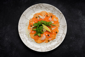 Salmon carpaccio with parmesan cheese, arugula and lemon
