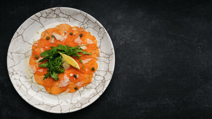 Salmon carpaccio with parmesan cheese, arugula and lemon