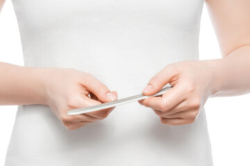 Cropped shot of a woman in a white t-shirt filing her nails. Close up, isolated.