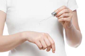 Obraz na płótnie Canvas Cropped shot of a woman in white t-shirt holding a pipette with serum, isolated on white. Nice short natural nails.