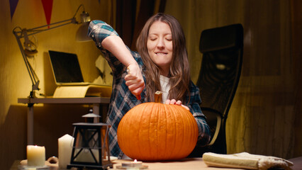 Preparing pumpkin for Halloween. Woman sitting and carving with knife halloween Jack O Lantern...