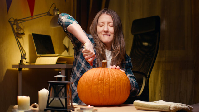 Preparing Pumpkin For Halloween. Woman Sitting And Carving With Knife Halloween Jack O Lantern Pumpkin At Home For Her Family.