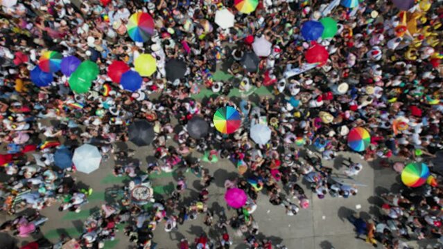 Isolated Rainbow umbrella in middle of a big crowd of people celebrating pride on city streets - Aerial view
