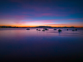Colours of Dawn over the bay with boats and high cloud