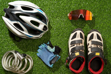 Flat lay composition with different cycling accessories on green grass background.