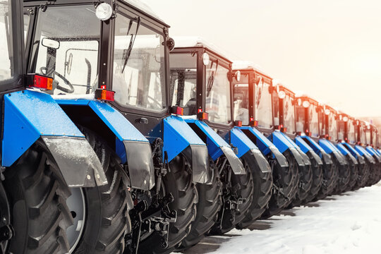 Many Different Tractors Standing In Row At Agricultural Fair For Sale Outdoors.Equipment For Agriculture.Heavy Industrial Machines Presented To Agricultural Exhibition. Agribusiness Leasing Concept