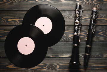Retro style clarinet and vinyl records on the flat lay wooden desk background.