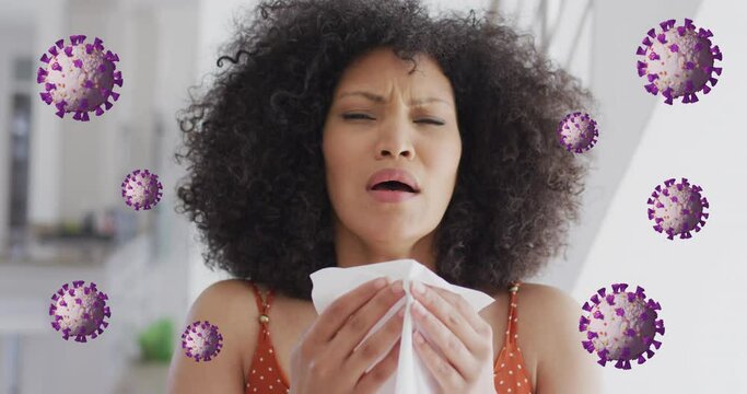 Animation of coronavirus cells rotating over biracial woman with afro hair sneezing with tissue