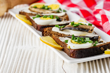canapes with sprats on a white rustic wooden background
