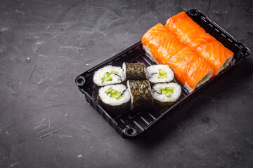 delicious sushi rolls in a delivery box on a black background