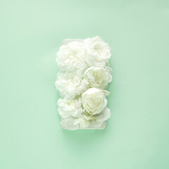 Phone cavered by bouquet of white roses on green background 