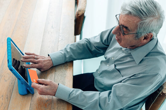 Old Man Using Credit Bank Card On The World Wide Web Internet With Tablet