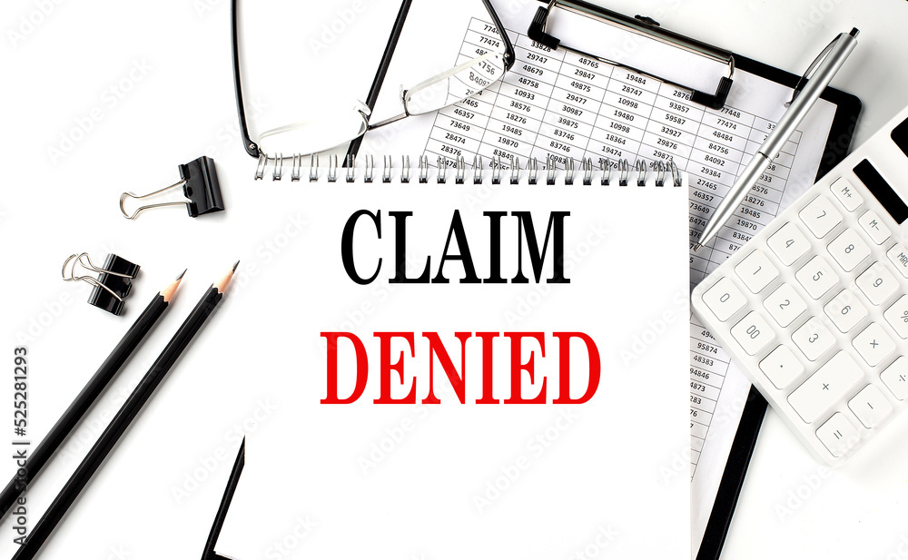 Poster text claim denied on office desk table with keyboard, notepad and analysis chart on white background