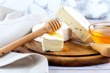 Camembert cheese with honey on a wooden board.