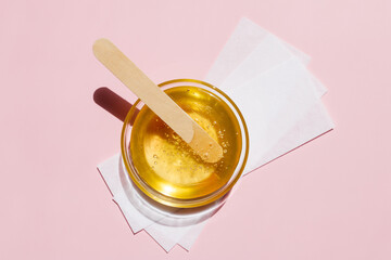 Liquid yellow sugar paste, wooden spatula, depilatory strips on a pink background. Removing unwanted hair. Sugaring. Depilation. Epilation. Beauty. Top view. - obrazy, fototapety, plakaty