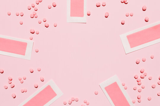 Pink depilatory wax strips, depilatory wax granules on a pink background. Place for text. Epilation, depilation, removal of unwanted hair. Top view.