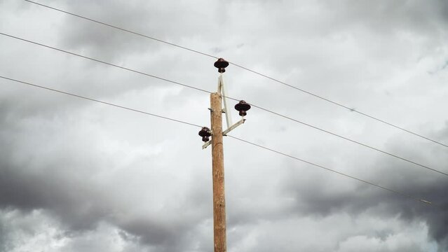 Wooden Telephone Pole And Cables With Dark Gloomy Sky In The Background. - low angle