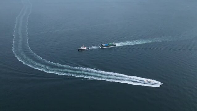 High-speed ferry passing slow tug and barge in calm open water