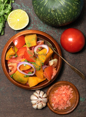 Healthy food pumpkin tomato salad on metal background top view.