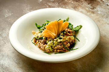 Oatmeal with avocado mousse and mango in a bowl. Selective focus, close-up