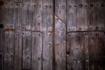 Fototapeta premium Antique weathered double leaf door with metal knockers and decorations on dark natural wood