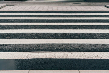 Empty crosswalk on wet  asphalt road. Black and white zebra crossing.