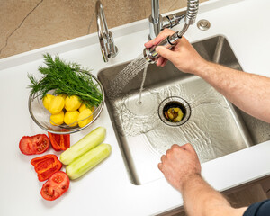 A man washes food waste into a dispenser