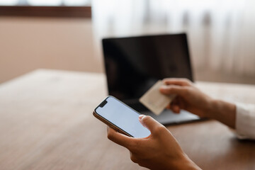 woman hands using smartphone and laptop computer for online shopping at home, Hand holding mobile phone with Payment Detail page display and credit card, online shopping concepts.