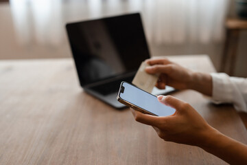 woman hands using smartphone and laptop computer for online shopping at home, Hand holding mobile phone with Payment Detail page display and credit card, online shopping concepts.
