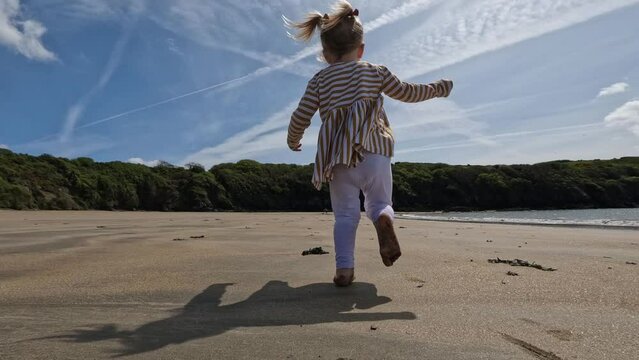 Young toddler runing on the beach follow shot
