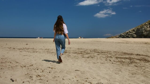 Young woman walking on the warm sand on the beach of Mallorca.