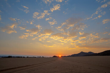 Fototapeta na wymiar Sun rise on the horizon where two sand tracks join