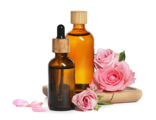 Fototapeta na wymiar Bottles of essential rose oil and flowers on white background