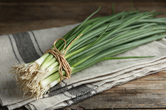 Fresh green spring onions on wooden table, closeup