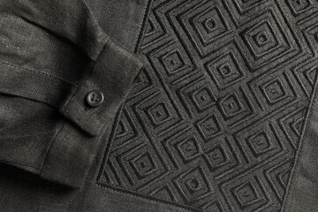 Black shirt with beautiful embroidery design as background, top view. Ukrainian national clothes