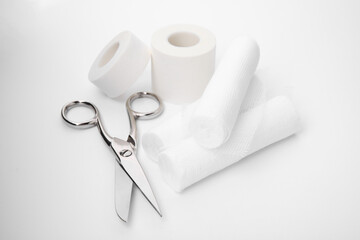 Medical bandage rolls, sticking plaster and scissors on white background