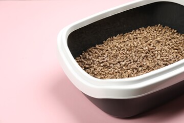 Cat litter tray with filler on pink background, closeup