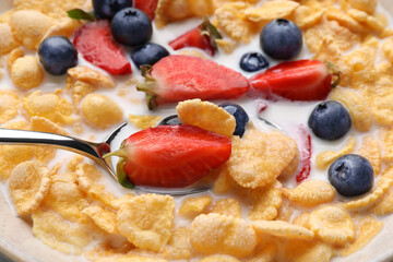 Bowl of tasty crispy corn flakes with milk and berries, closeup