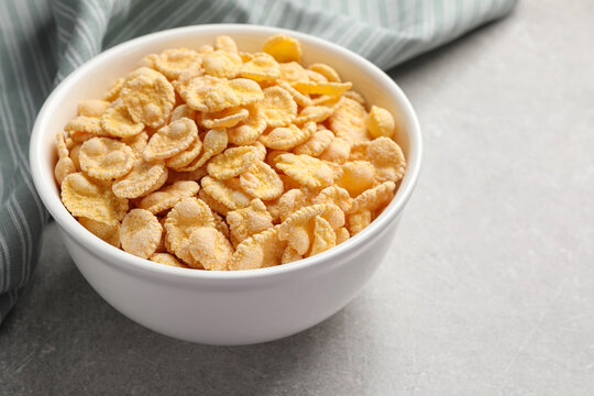 Bowl of tasty corn flakes on light grey background, closeup. Space for text