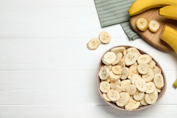 Freeze dried and fresh bananas on white wooden table, flat lay. Space for text