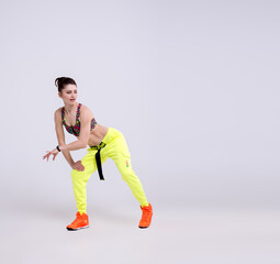 Attractive sporty woman wearing bright yellow pants dancing against a white background. Dispersion and light flare effect on Woman's body silhouette.