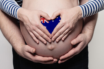 Australian family concept. Man embracing pregnant woman belly and heart with Australian flag colors closeup