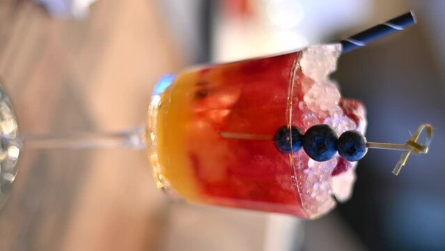 Red cocktail with vodca with mango juice and ice, blueberries