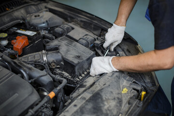 Auto mechanic working under car hood in repair garage