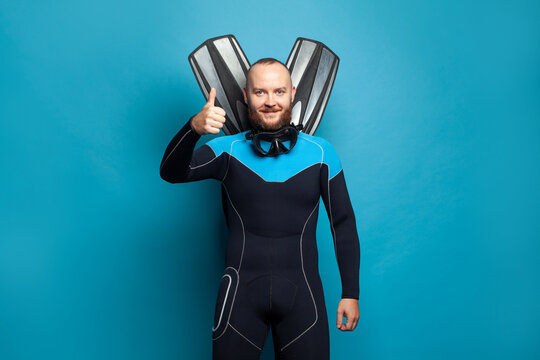Sport and traveling concept. Joyful diver man showing thumb up on blue background
